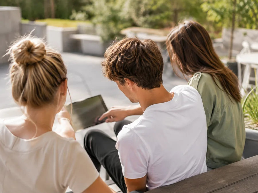 Drei Studierende schauen gemeinsam auf ein Tablet und klären ihre Steuererklärung